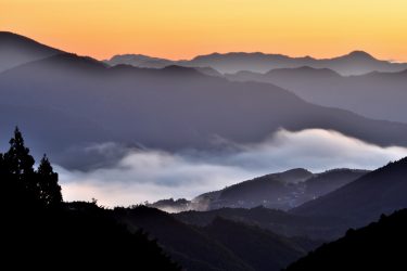 奥ゆかしき熊野古道の雲海風景。日の出直後、山深い土地にある集落と大斎原（おおゆのはら）の大鳥居を俯瞰撮影 和歌山県本宮町